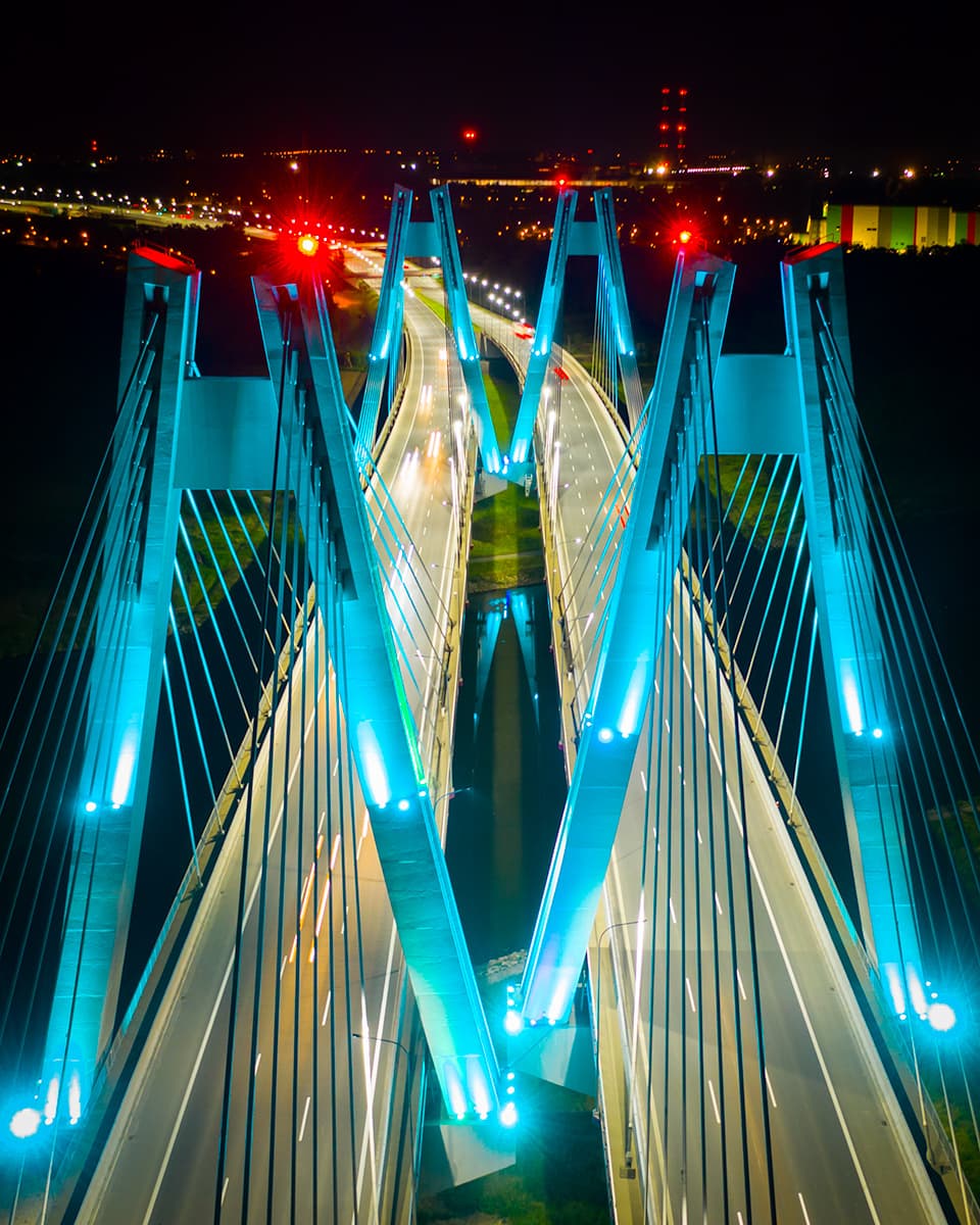Most na Wiśle nocą oświetlony w kolorze morskim w ujęciu z drona Kaktus.studio