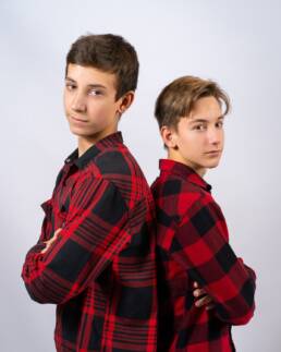 Portret dwóch kolegów szkolnych stojących plecami do siebie w czerwonych koszulach w kratę